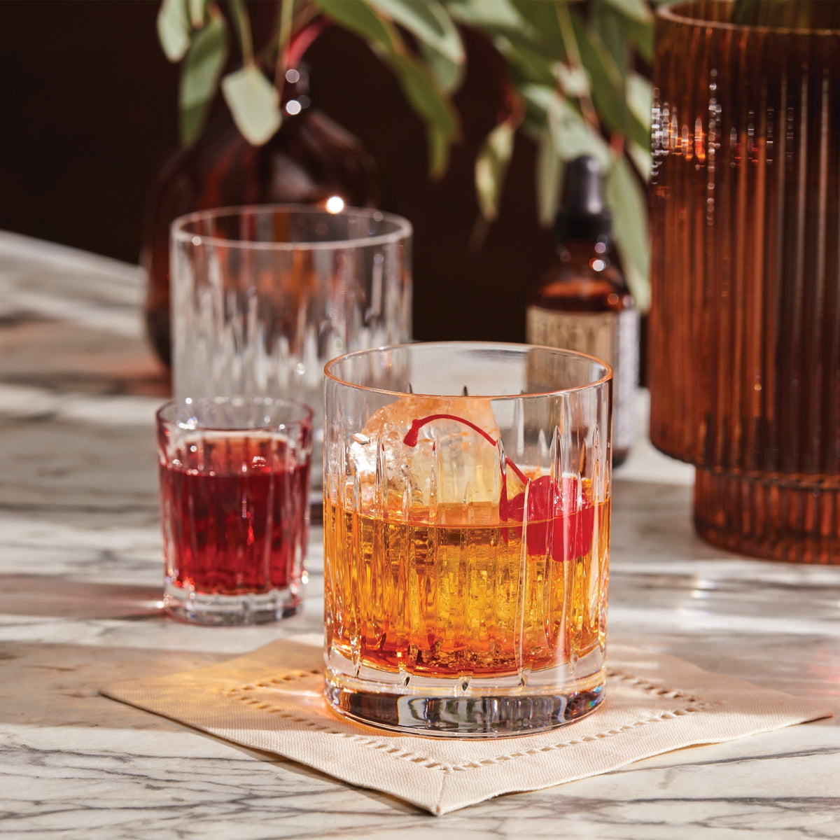 Crystal glasses with cocktails on a marble table, garnished with a cherry.